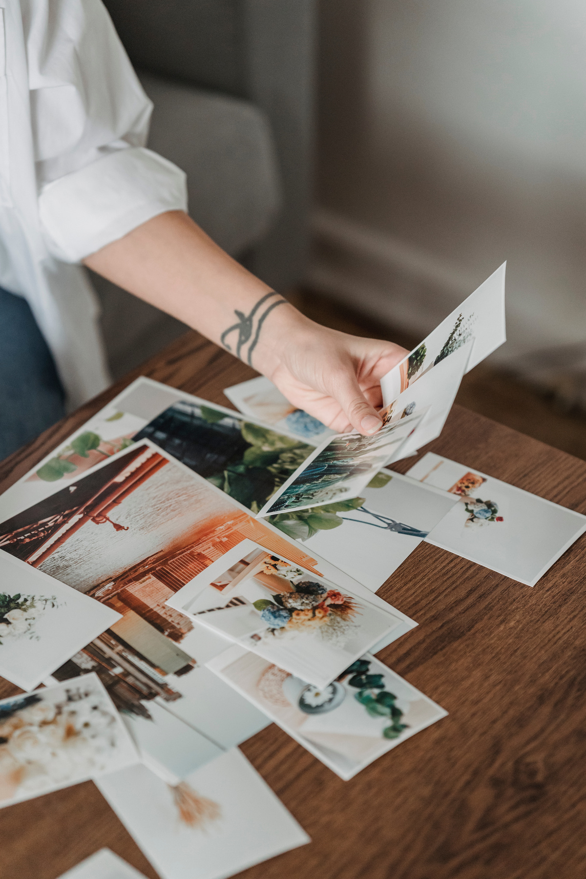 Crop unrecognizable woman looking through printed photos